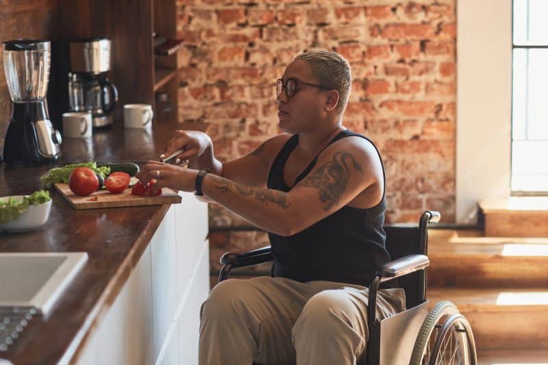 A disabled person cooks food in her kitchen in Southern California.