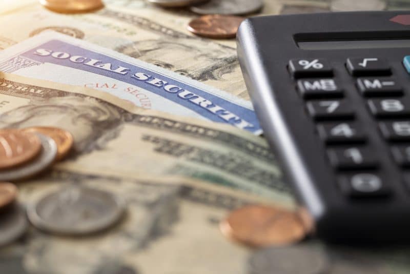 A social security card surrounded by money and a calculator.