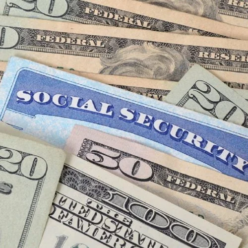 A Social Security card partially tucked between $20, $50, and $100 bills.