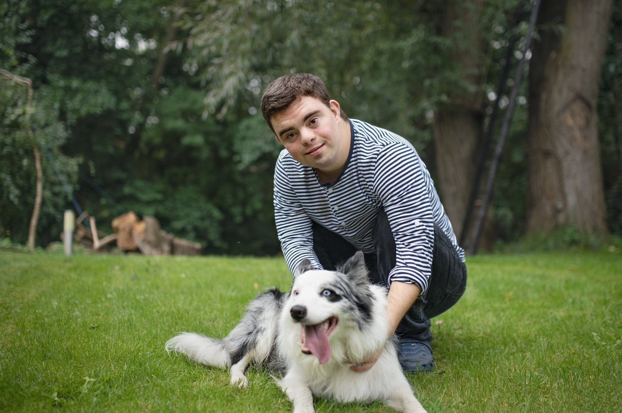 A young man with special needs petting his dog.